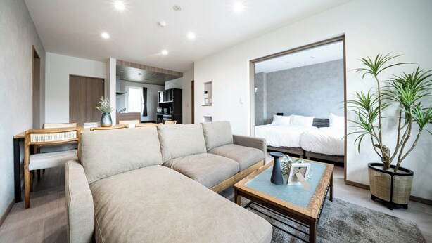 Una sala de estar moderna con un sofá, una mesa de centro y un comedor. Se ve una cama al fondo, con vistas a la ciudad.