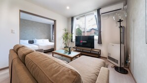 Una habitación de hotel moderna con una cama grande, un sofá, un televisor y una planta.