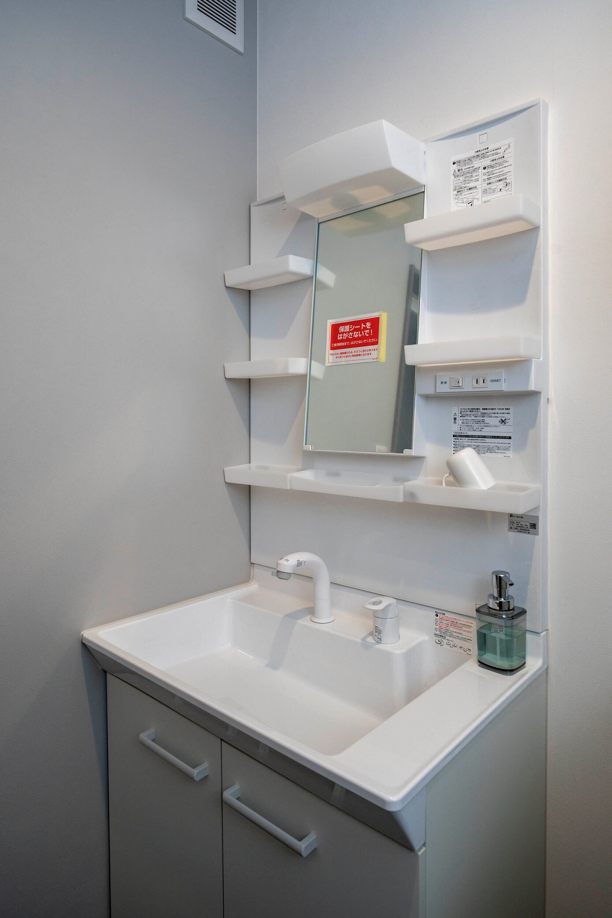 A bathroom with a white sink, mirror, and shelves.