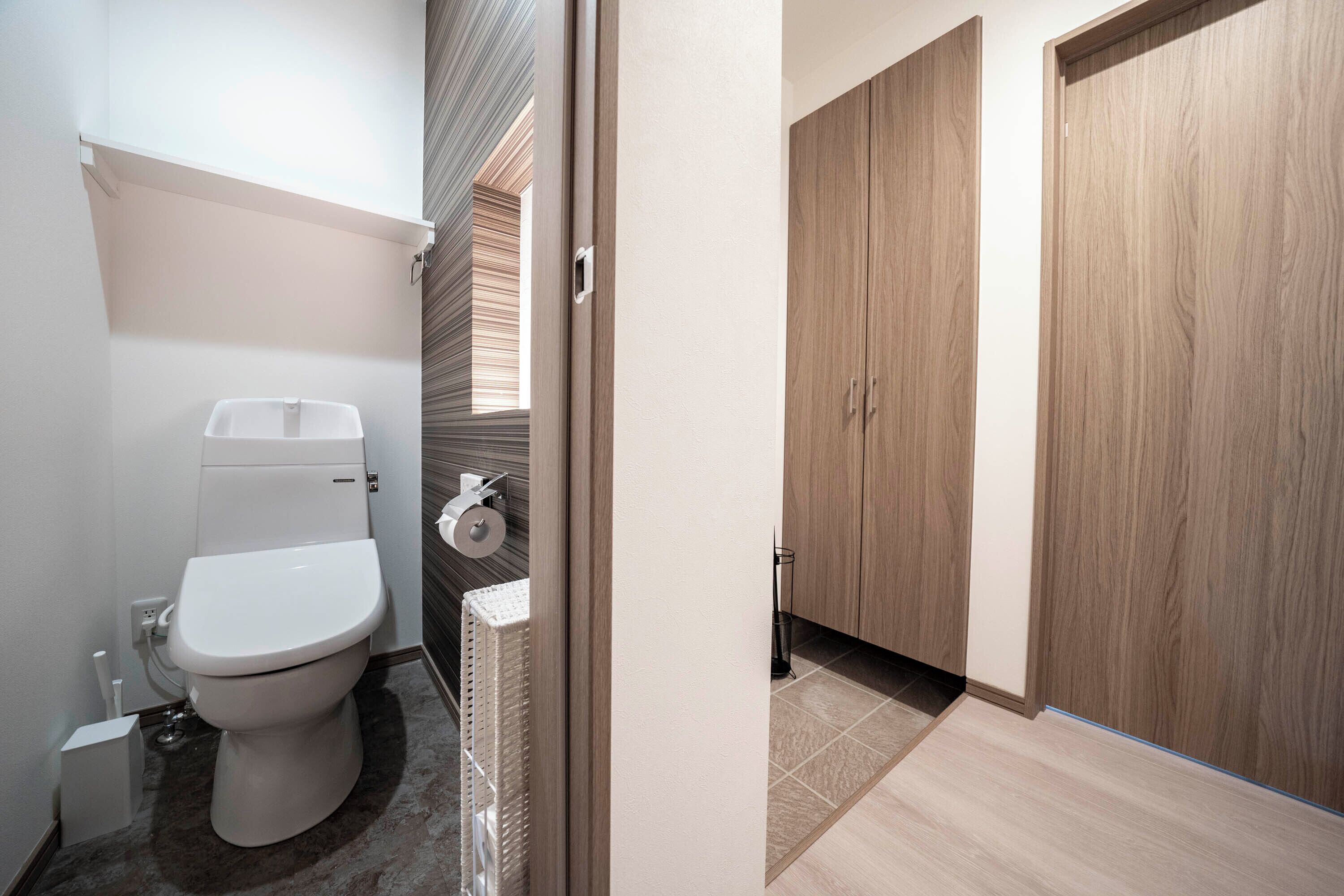 Een moderne badkamer met toilet, handdoekhouder en douchehoek.