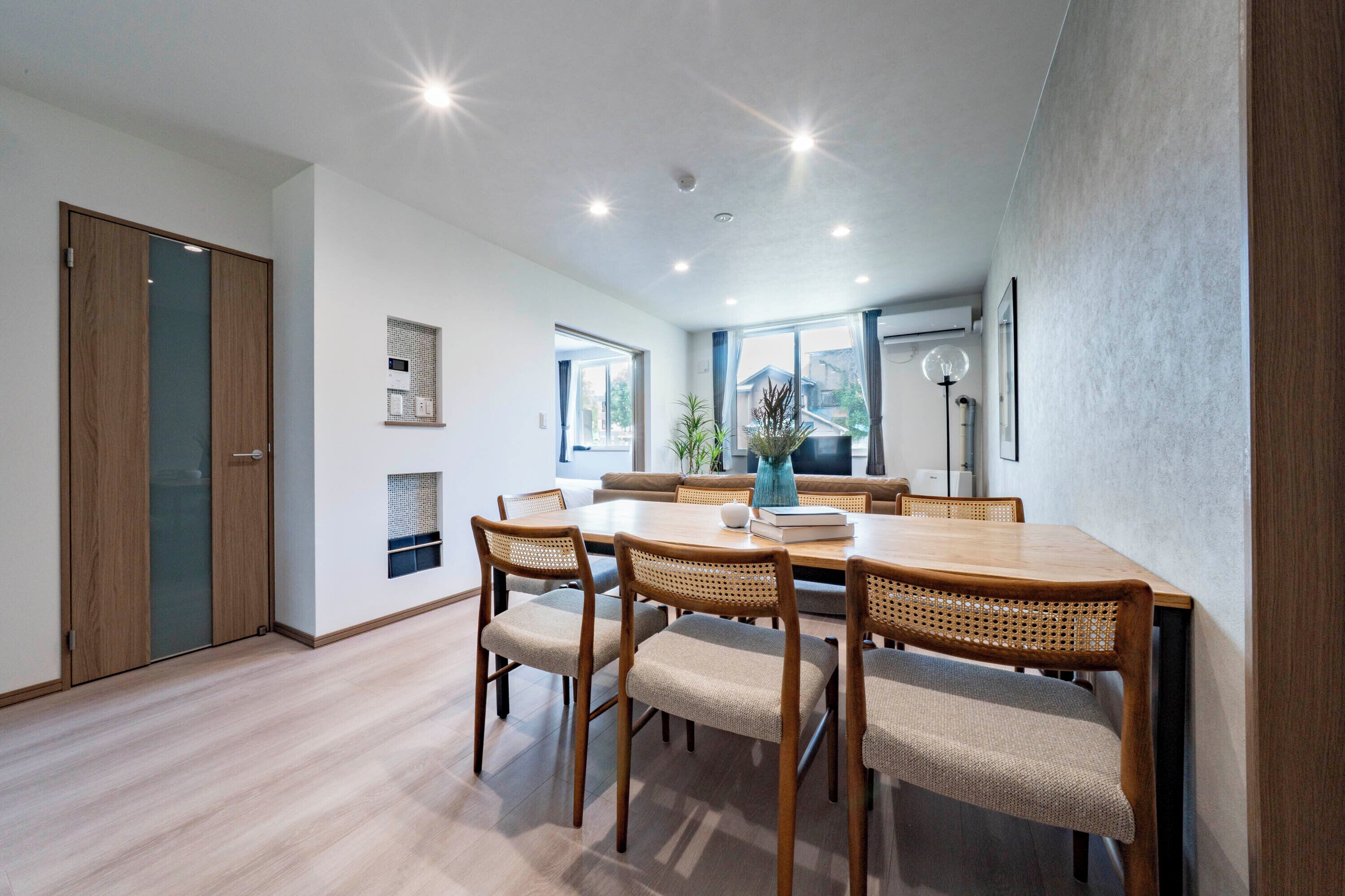 A dining area with a wooden table and chairs, a vase, and a view of the outside.