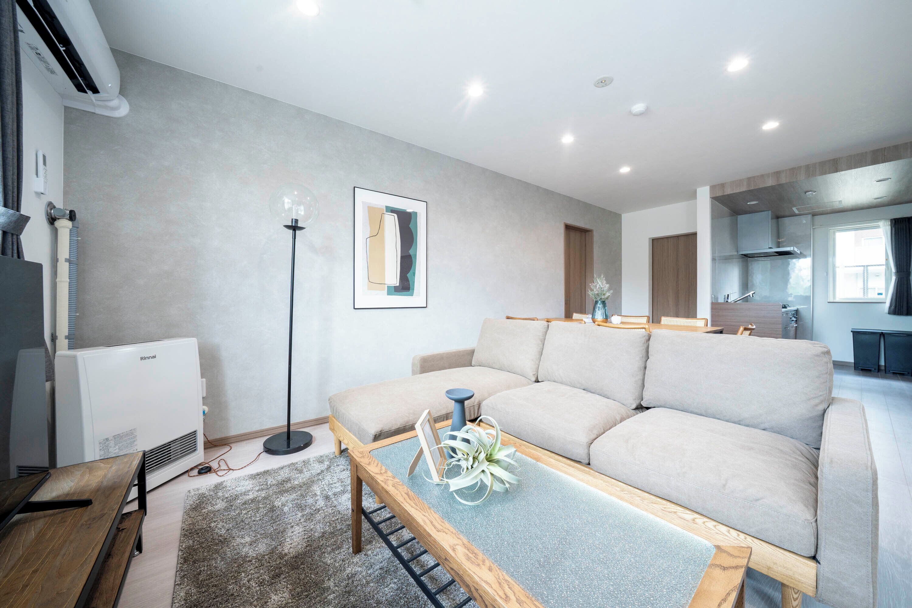 Un salon moderne avec un canapé beige, une table basse en bois et un lampadaire.