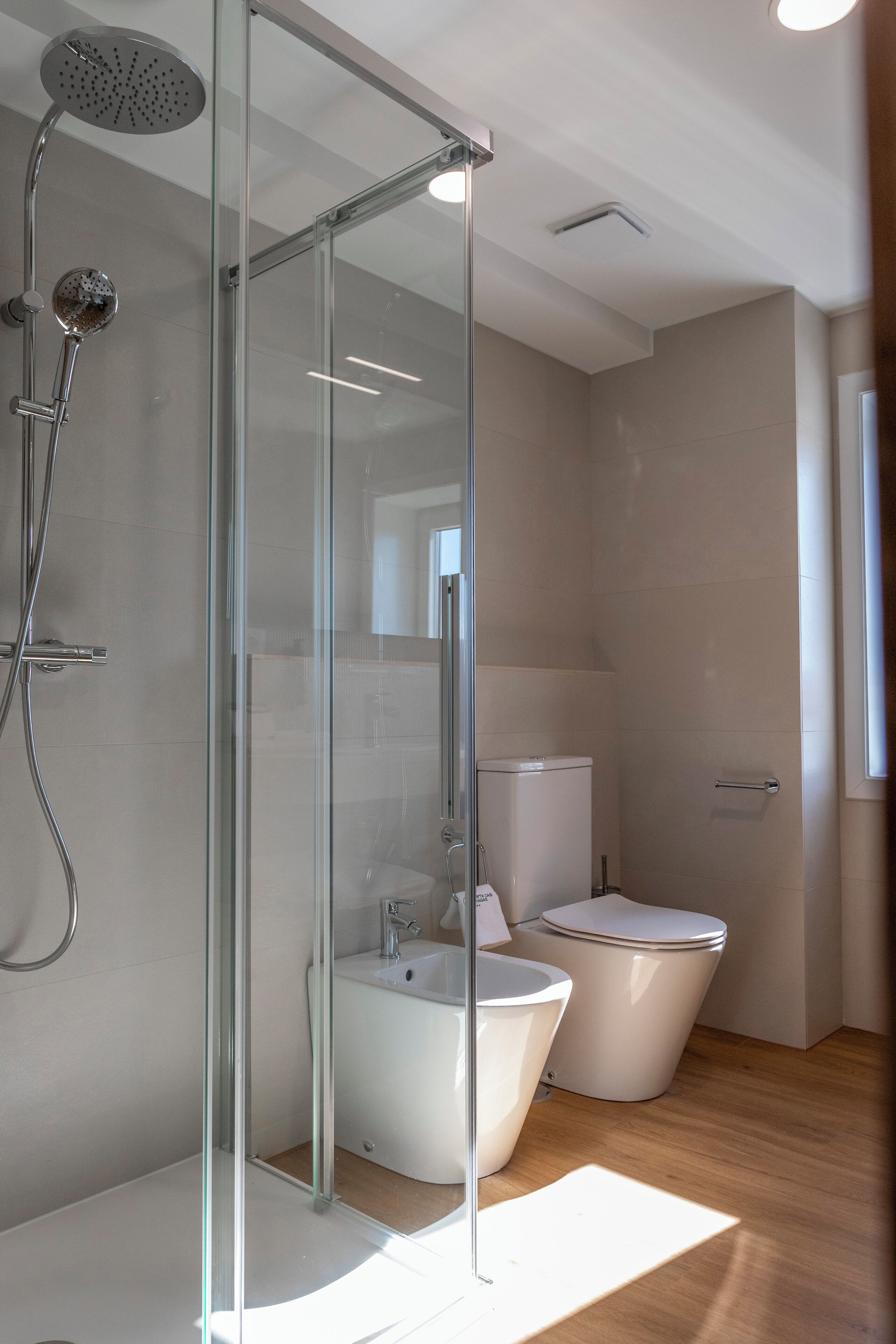 Ein modernes Badezimmer mit einer gläsernen Dusche, einer freistehenden Badewanne und einem WC.