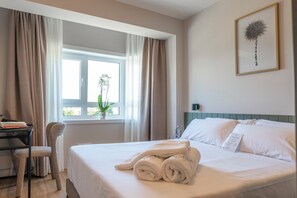 A hotel room with a bed, a desk, a chair, and a window with curtains. - SNÖ Porta das Fragas (A Capela)