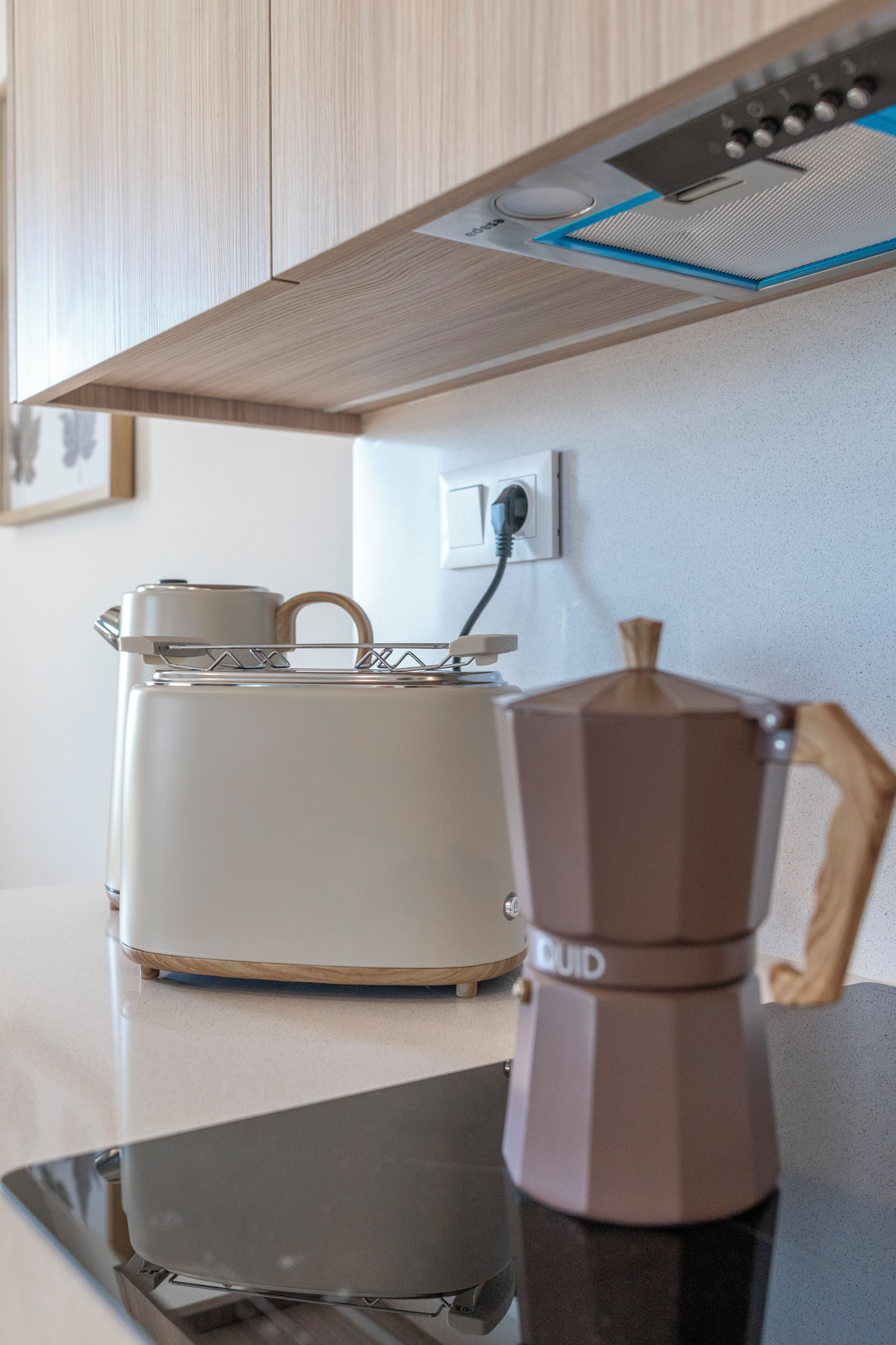 Una cocina con cafetera, tostadora y un enchufe.