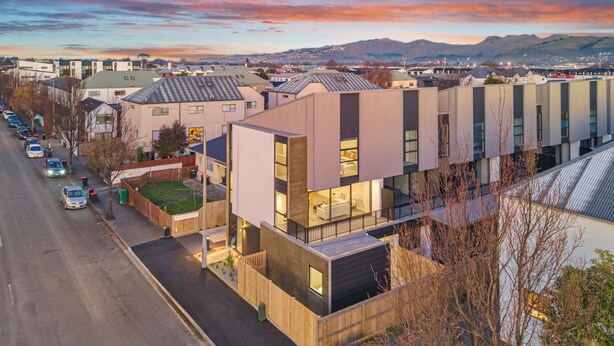 A modern building with a flat roof, large windows, and a visible outdoor area with a fence. - Spacious 3 Bedroom Townhouse - Close to Stadium (Christchurch)