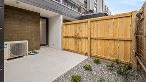 A modern residential building with a concrete patio, a wooden fence, and a small garden area. - Spacious 3 Bedroom Townhouse - Close to Stadium (Christchurch)