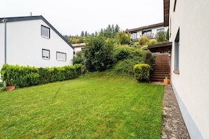 A residential property with a well-maintained lawn, a staircase leading to a second floor, and a white exterior wall. - Apartment 'Kinzigtalblick' with Mountain View, Private Terrace and Wi-Fi (Wolfach)
