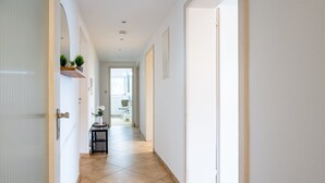 Ein Flur mit Fliesenboden, weißen Wänden und einer Tür zum Badezimmer.