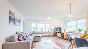 Ein modernes Wohnzimmer mit einer Couch, einem Esstisch und einem Fernseher.