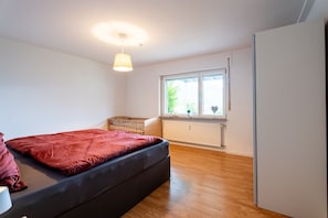 A bedroom with a bed, a window, a radiator, and a wardrobe. - Apartment 'Kinzigtalblick' with Mountain View, Private Terrace and Wi-Fi (Wolfach)