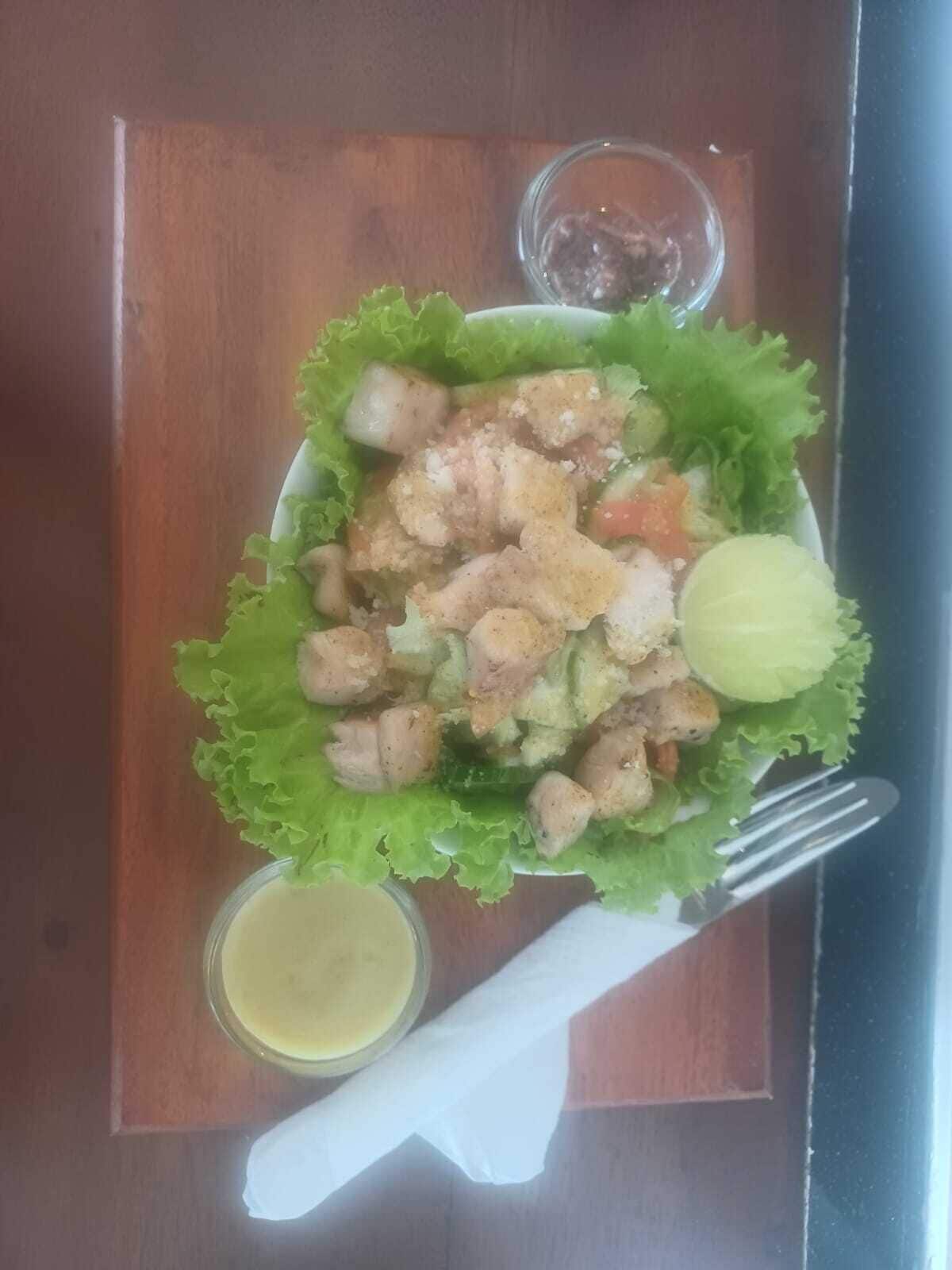 A meal with croutons, vegetables, and a lemon wedge on a wooden table.