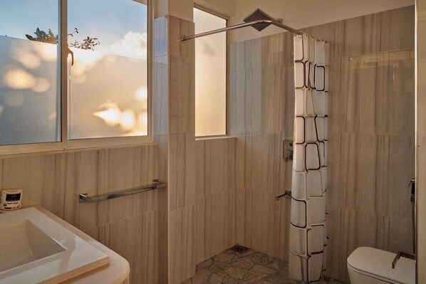 Een badkamer met douche, toilet en wastafel.