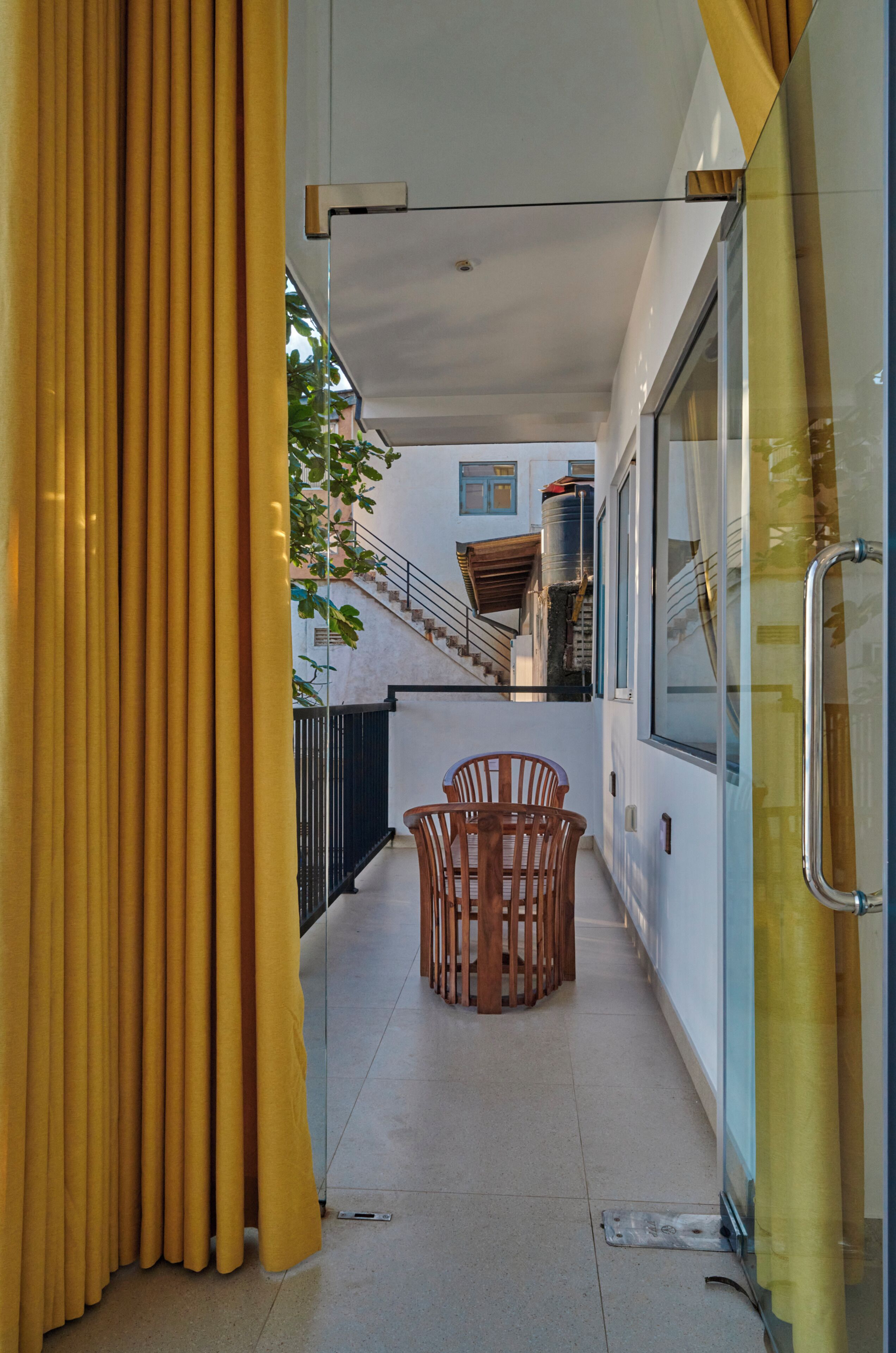 A corridor with a table and chairs, a staircase, and a glass door.