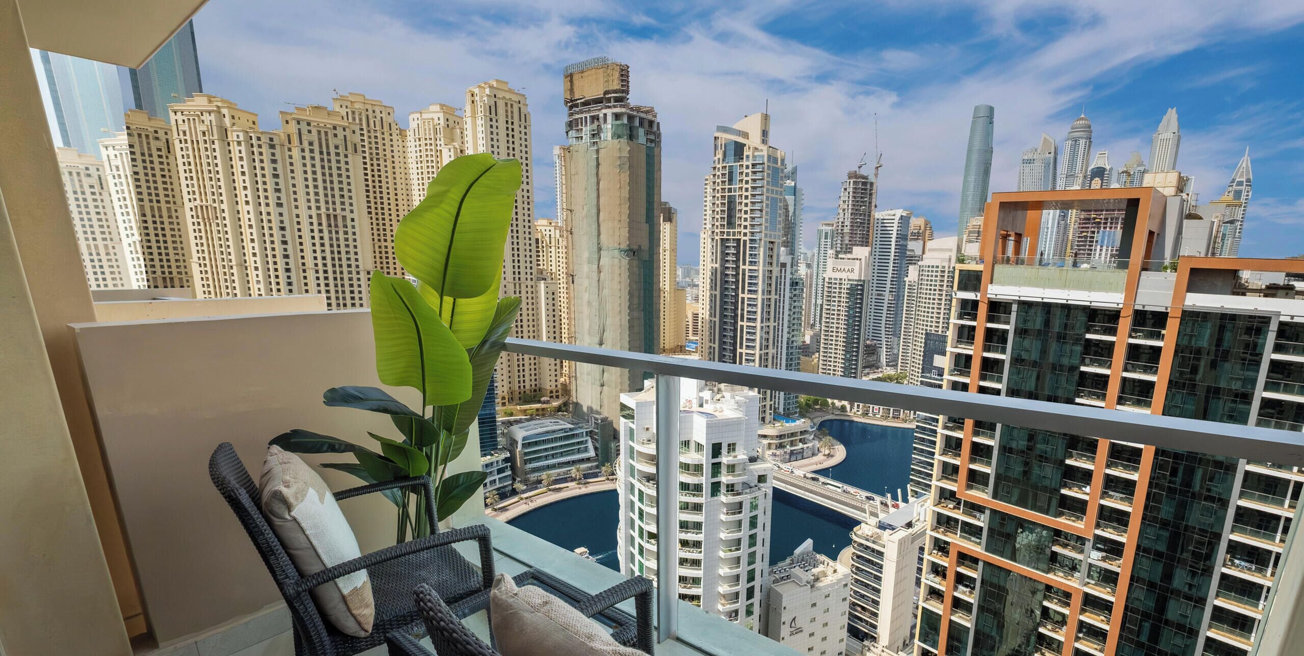 A balcony with a view of a cityscape, including high-rise buildings and a body of water.