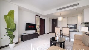 Une chambre d’hôtel moderne comprenant un coin salon, une table à manger, un canapé, une télévision et un coin cuisine.
