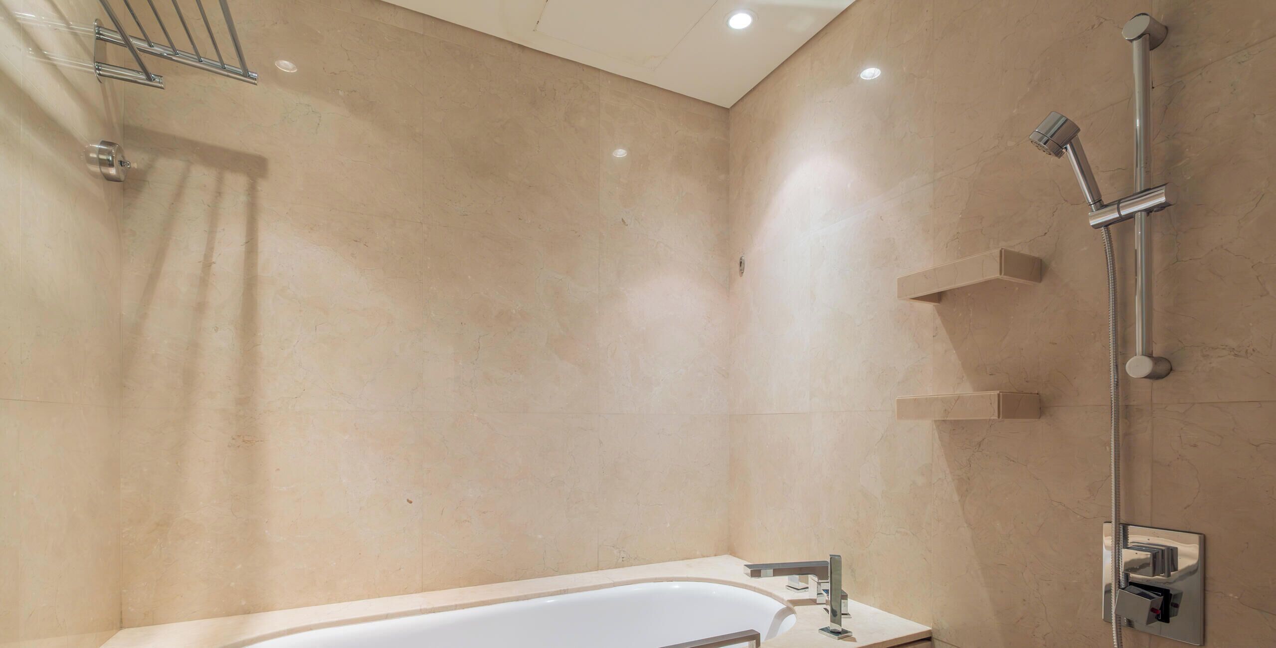 A modern bathroom with a freestanding bathtub, a handheld showerhead, and a towel rack.