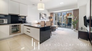 Une cuisine moderne dotée d’un îlot central, d’un coin repas avec un canapé et des fauteuils, et d’une grande fenêtre offrant une vue sur la ville.
