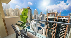Un balcon agrémenté de meubles en osier, d’une plante en pot et offrant une vue sur les gratte-ciel de Dubaï.
