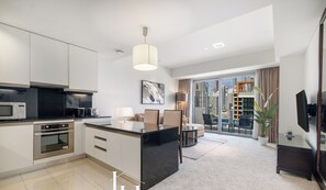 Une cuisine moderne dotée d’un îlot central, d’un coin repas avec un canapé et des fauteuils, et d’une grande fenêtre offrant une vue sur la ville.