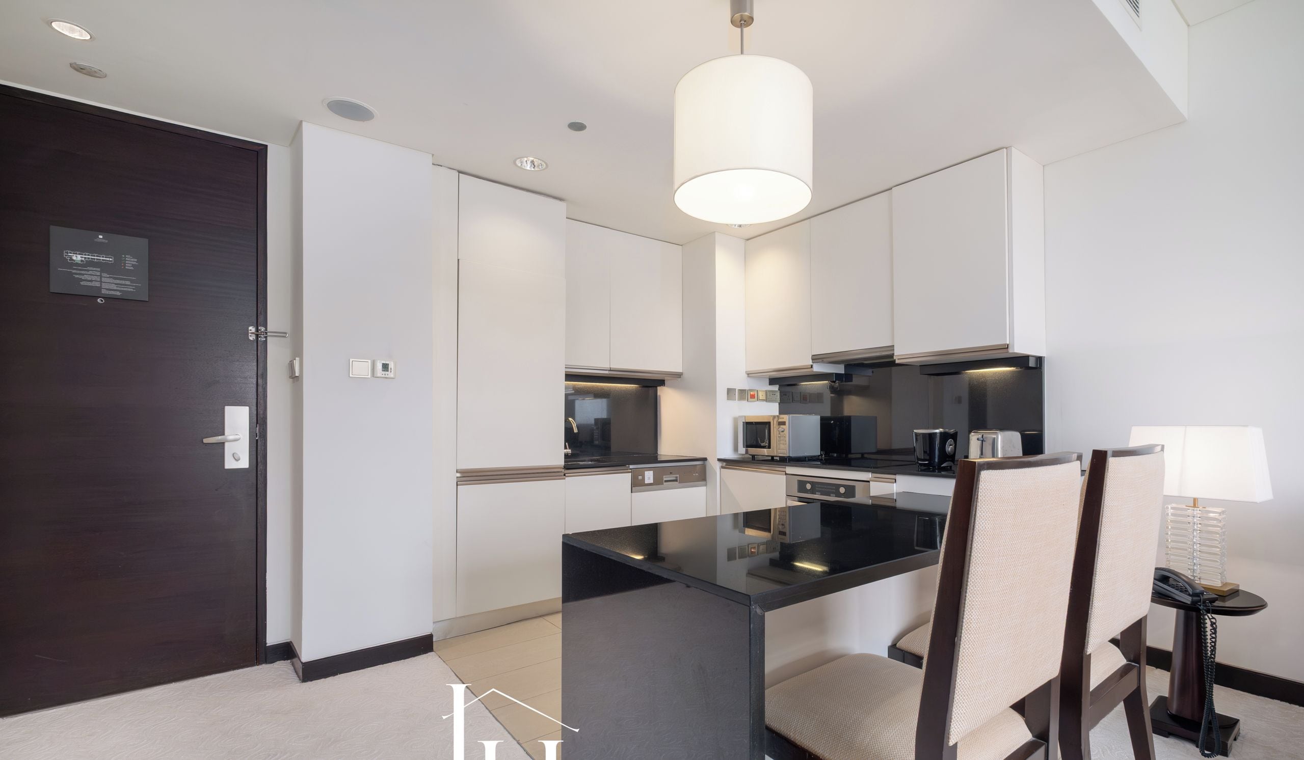 A modern kitchen with a central island, dark cabinetry, and a hanging light fixture.