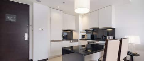 A modern kitchen with a central island, dark cabinetry, and a hanging light fixture.