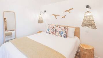 A bedroom with a bed, a mirror, wall-mounted lights, and decorative wall art.