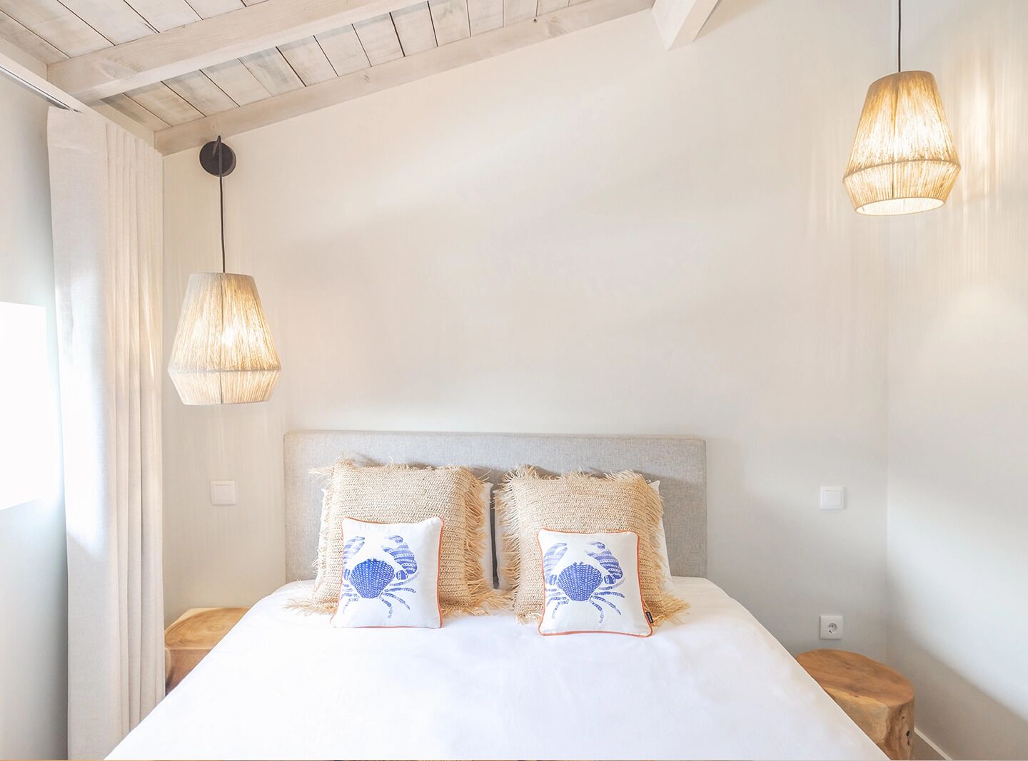Ein Schlafzimmer mit einem Bett, zwei Kissen mit Krabbildern und zwei Hängeleuchten.