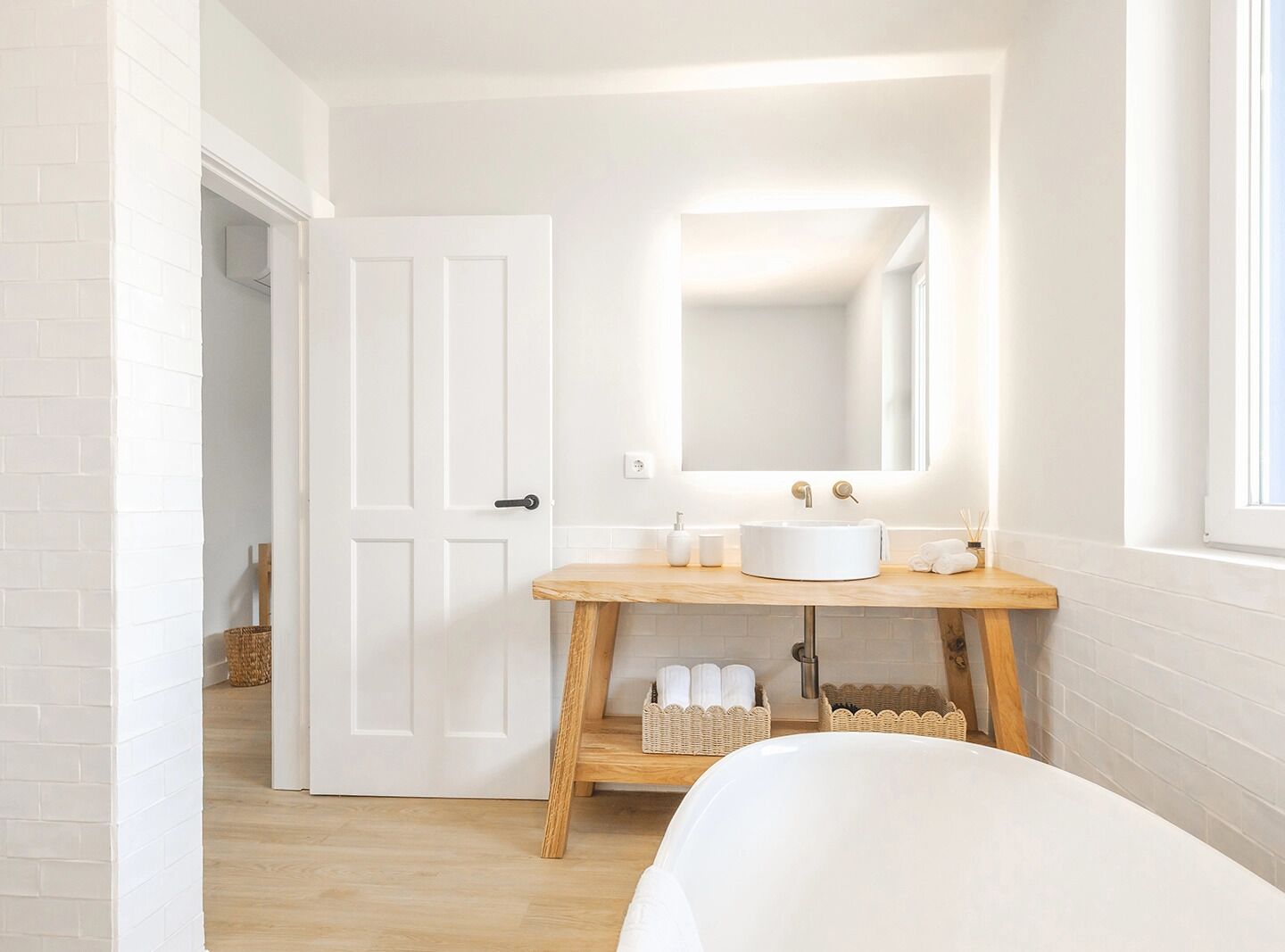 A bathroom with a white sink, wooden vanity, and a large mirror.