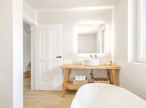 A bathroom with a white sink, wooden vanity, and a large mirror.