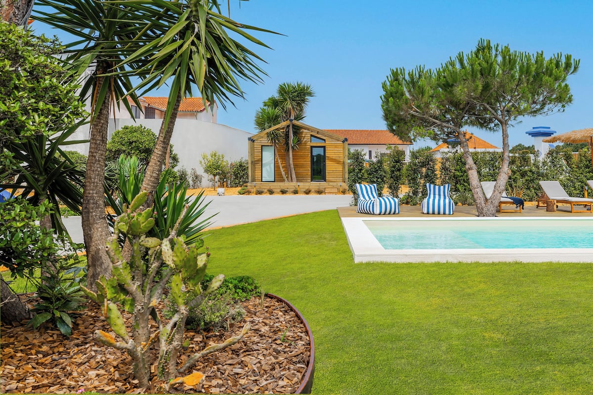 A poolside area with a small wooden structure, lounge chairs, and a well-maintained lawn.
