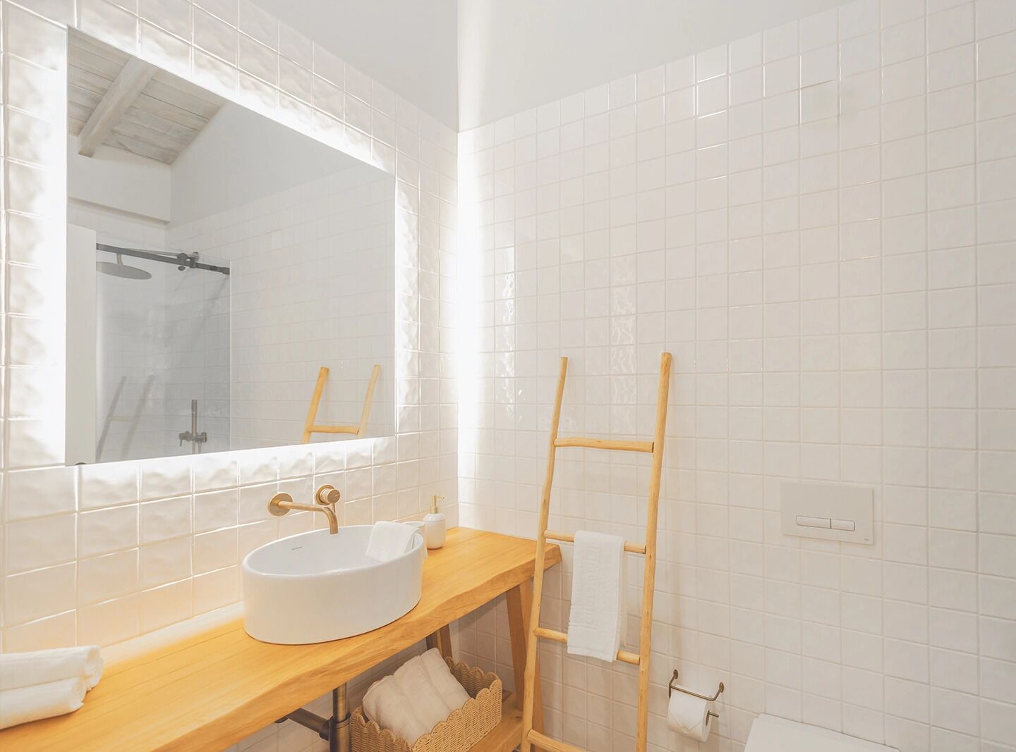 A bathroom with a round white sink, a wooden vanity, a mirror, and a towel rack.