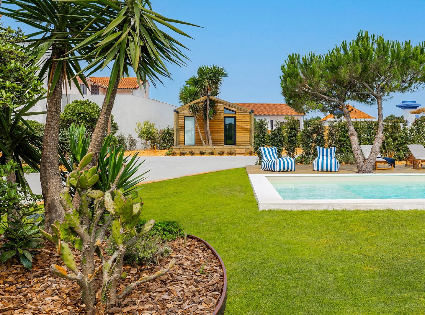 A poolside area with lounge chairs, a small wooden structure, and a well-maintained lawn.