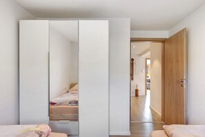 Ein Schlafzimmer mit einem Bett, einem Kleiderschrank und einer Tür zu einem anderen Raum.
