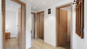 Un couloir avec des portes en bois, un porte-manteau fixé au mur et une petite table avec une lampe.