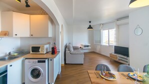 Ett kompakt bostadsutrymme med ett kök, en matplats och en sittgrupp med en soffa.