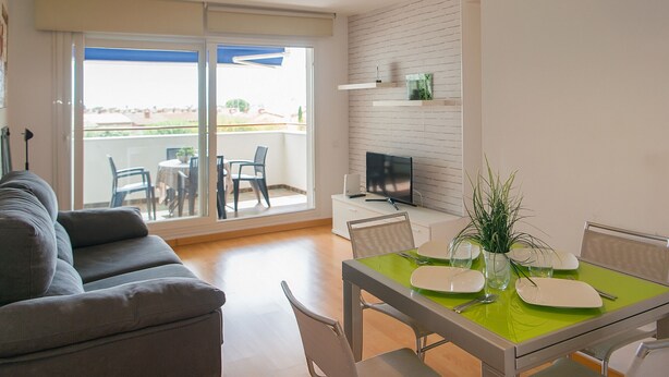 A modern living room with a sofa, dining table, chairs, a flat-screen TV, and a balcony with a view. - WELCS APARTMENT 287 EMP with public swimming pool (Rosas / Roses)