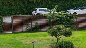 A swimming pool with a tiled deck, metal ladders, and a grassy area with a fence and parked cars in the background. - WELCS APARTMENT 287 EMP with public swimming pool (Rosas / Roses)