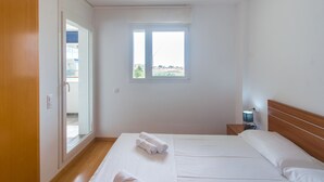 A bedroom with a large bed, a nightstand with a lamp, and a window with a view of the outside. - WELCS APARTMENT 287 EMP with public swimming pool (Rosas / Roses)