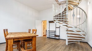 A spiral staircase with wooden steps and white railings, a wooden dining table with chairs, and a door leading to another room.