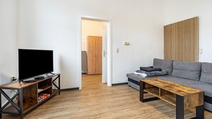 A modern living room with a flat-screen TV on a wooden stand, a grey sofa, and a coffee table.