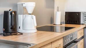 A kitchen with a coffee maker, a kettle, and a microwave.