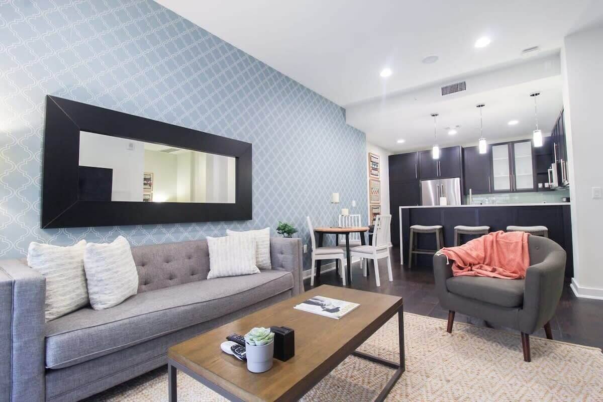 A living room with a grey sofa, a coffee table, and a dining area with a table and chairs.