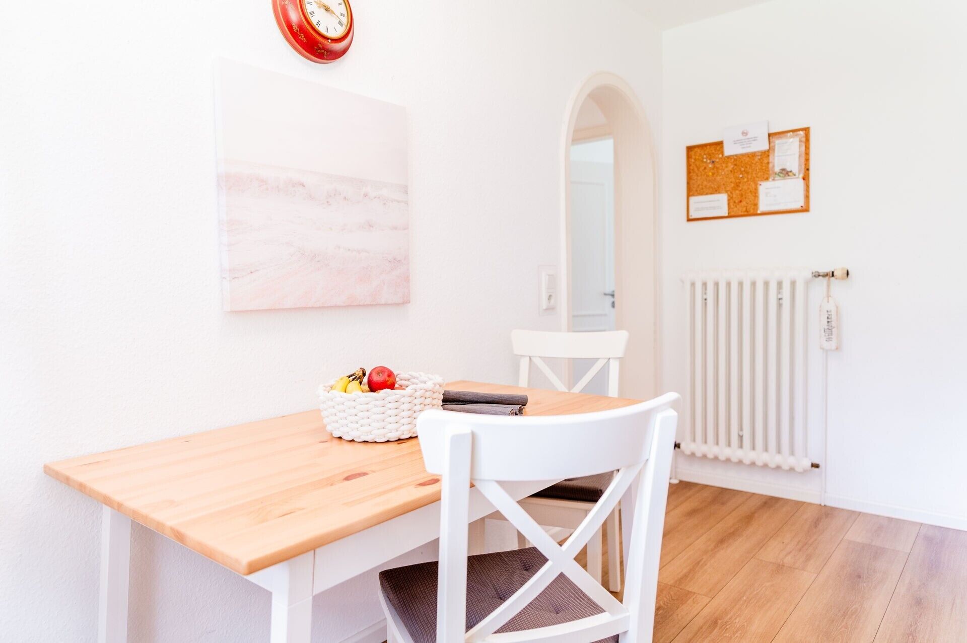 Un comedor con una mesa de madera, una silla blanca y una cesta de frutas.