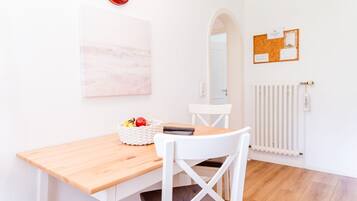 Un comedor con una mesa de madera, una silla blanca y una cesta de frutas.