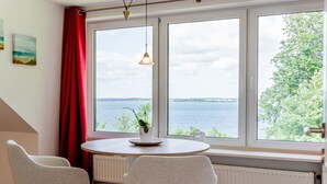 A room with a large window, two chairs, a table, and a hanging light fixture. - Holiday Home 'Seeblick' with Sea View, Private Terrace and Wi-Fi (Langballig)