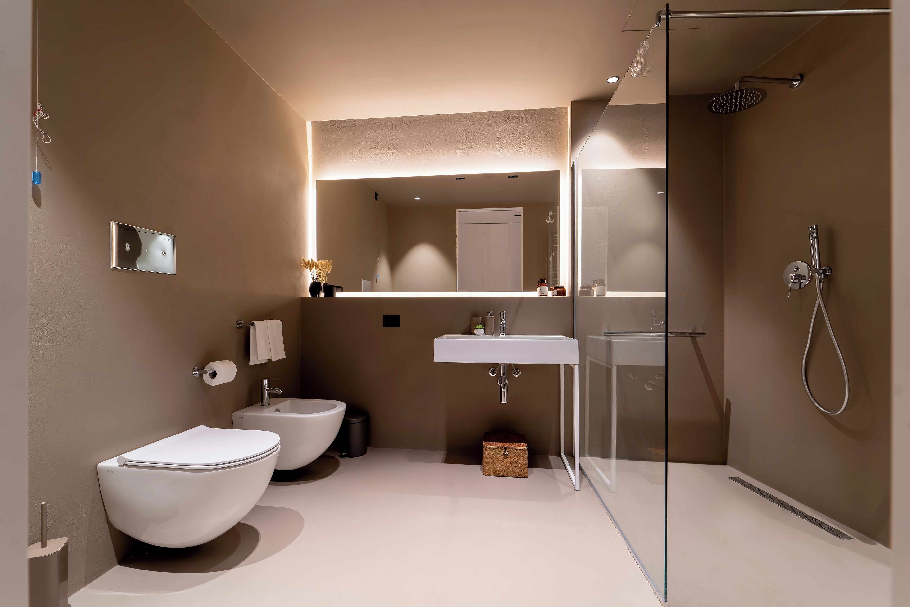 Een moderne badkamer met een douche met glazen wand, twee wasbakken en een bidet.