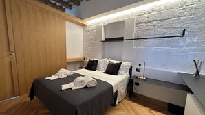 A modern hotel room with a bed, wooden wardrobe, and a wall-mounted shelf. - Gonia Residence (Trapani)