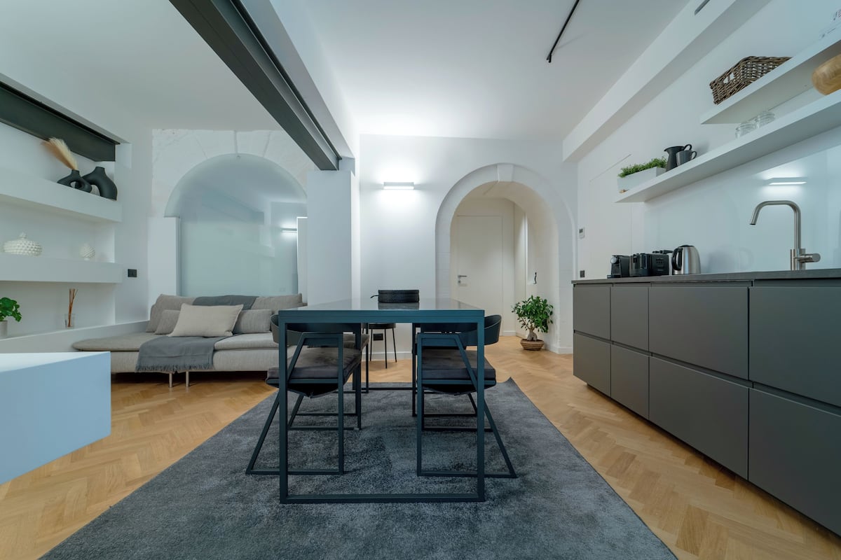 A modern kitchen with a dining area, a sofa, and a coffee machine.