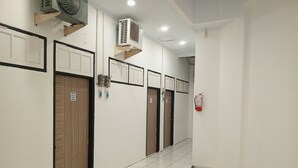 A hallway with doors, an air conditioning unit, and a fire extinguisher. - PBINN Tamastu House Pasar Baru (Jakarta)